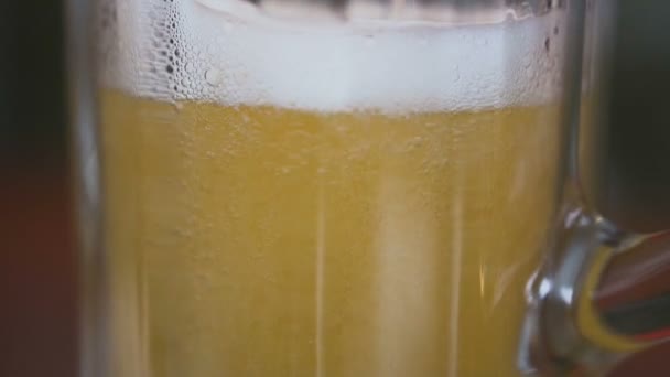 Nahaufnahme. Auf dem Tisch steht ein leeres Glas, in das Bier mit Schaum gegossen wird — Stockvideo