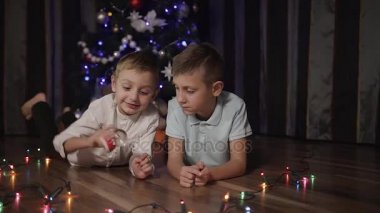 İki genç çocuklar bir Noel ağacı önünde yalan ve kar küresi ile oynayan bir Noel Baba olan iç