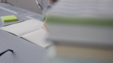 Masada oturur ve bir ev ödevi yapan bir öğrenci için büyük bir plan. Bir öğrenci bir resim çizer. Çocukta bir cetvel, kalem ve çizim için albüm yok