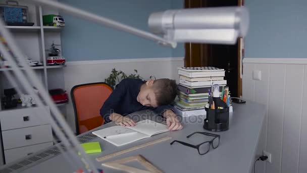 Skolan barn göra läxor. Skolan pojken gör sina läxor hemma, elev har varit uttråkad på lektionen. Söt vacker pojke hans lärdom hemma och sover på bordet, tillbaka till skolan — Stockvideo