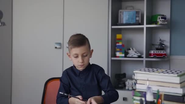 Ένας μαθητής χρωματίζει μια εικόνα από την εργασία του στο σχολείο. Το αγόρι έχει ένα χάρακα στα χέρια του και ένα μολύβι. Ένας φοιτητής κάθεται στο σπίτι στο σπίτι και να κάνει μαθήματα — Αρχείο Βίντεο