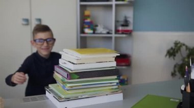 Yakın çekim yakışıklı bir çocuğun hikayesini gözlük takar, masanın arkasında hangi o ödev ve kitapları ile eğlenceli hugs için çalışır. Ev ödevi