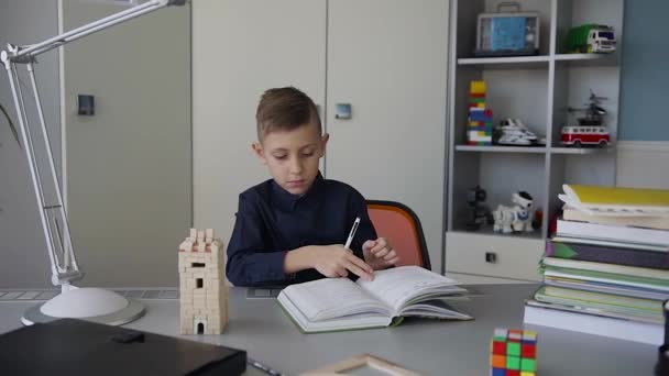 A nice guy flipping through the pages of an interesting book. A schoolboy reads a book at home. A student makes a homework assignment — Stock Video