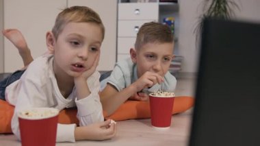 Leziz patlamış mısır yemek ve komik karikatür seyir odası turuncu yastıklar katta yatan güzel çocuk portresi