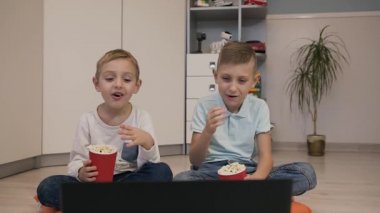 Güzel çocuk beyaz komik bir film izlerken ve leziz patlamış mısır yemek odası turuncu yastıklar katta oturan