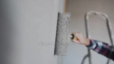 Çıplak duvar boya silindiri ile dışarı ile gri boya boyama. El boyama boya silindiri kullanarak. Ressam kız silindir boyama duvar, ressam ev kavramı ile iş yerinde