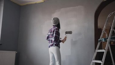 Güzel genç kız dairede tamirat yapar ve müzik ve dans, kadının duvar resmi yapması için dinler