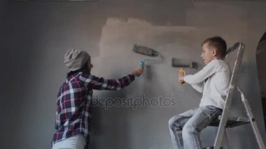 Genç kız ve erkek kardeşi duvarlar bir gri renkte yatak odasında bir rulo ile yıkayın. Evde badana, onarım
