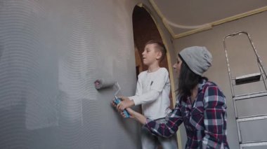 Genç kız ve erkek kardeşi resim Oda gri renk ve gülümseyerek. Yeni bir renk duvarlarında badana. Bir apartman dairesinde onarmak