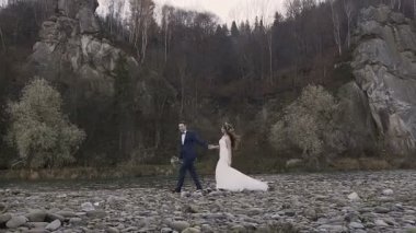 Gün batımında nehrin dağlarda dolaşan gelinler güzel genç çift. Bahar, sonbahar. Düğün kavramı