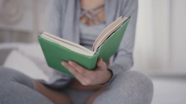 Yakın çekim A genç girl bir kitap onun elinde tutan, onu açın ve sayfaları okumaya başlamak için bırakır. Gözlük güzel genç kadın bir kitap açılır