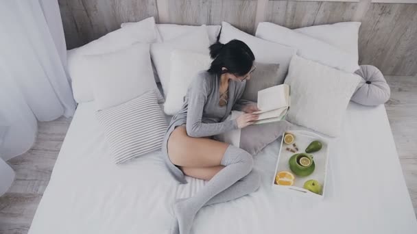 Genç bir kız evde, yatakta yorgun bir kitap okumak, yatmaya gitti ve uyudu. Genç bir kadın o dinlenmek ve uyuya kalmışım bir kitap koymak yatak yatak odasında bir kitap okumak — Stok video