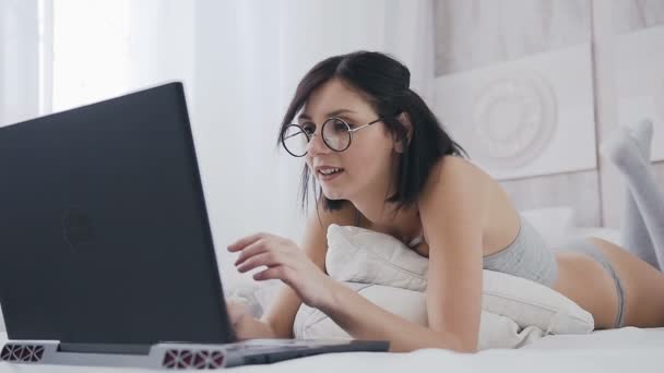 Милая 20-летняя женщина, работающая на ноутбуке кровать в спальне на кровати она счастлива, что работал хорошо. Красивое лицо рядом с эмоциями радости и счастливого успеха — стоковое видео