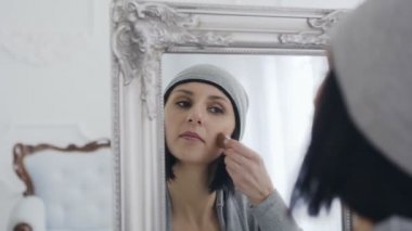 Güzel esmer kız makyaj yapıyor. Beyaz oda ve güzel ayna.