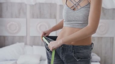 yakın çekim bir kadınla bir spor rakam zayıflama sonra onun pantolonunu boyutu ölçer. güzel vücut ve düz bir karın.