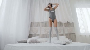 Genç kadın sabah kulaklık müzik keyfi. Kaygısız kız yatakta evde pop müzik dinleme sırasında atlar