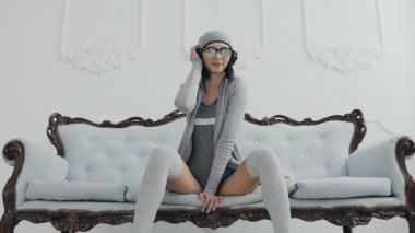 Genç seksi kız ya da siyah kulaklık kullanarak müzik dinleme kanepede oturan kadının müzik, gülümseyen, dinleme ve dans ise gülüyor. Kapalı, arka planda beyaz duvar