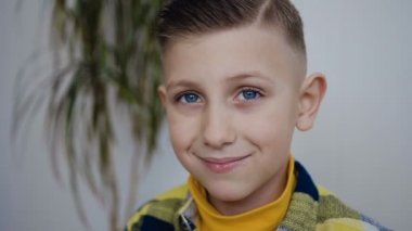 ndclose-up kameraya benzeyen küçük bir şık çocuk yüz güzel mavi gözleri var ve kırmızı Kupası ile lezzetli bir içki içiyor. Kapalı