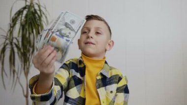 Güzel bir çocuk para sevinir. Görünümü bir çocuk Amerikan 100 sayma faturaları çocuk para hakkında mutlu. Beyaz arka plan, kapalı