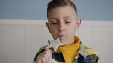 Yakın çekim. Küçük bir yakışıklı sarışın çocuk yiyor olması bir çubuk üzerinde lezzetli Kurabiye. Arka plan üzerinde beyaz, kapalı