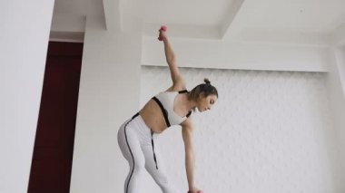 Tarafına bükme. Genç güzel kız tarafına bükme ve halter salonunda ise holding beyaz spor giyim. İçinde kapalı bir beyaz ve kırmızı zemin üzerine