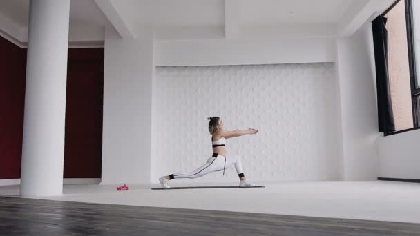 Menina loira bonita caucasiana fazendo ioga asana no chão no ginásio perto das grandes janelas. Treino de fitness. Calma e relaxamento, felicidade da mulher — Vídeo de Stock