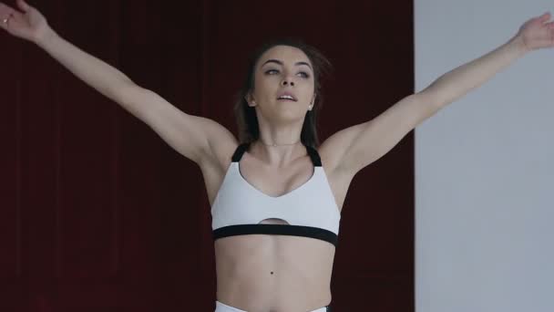 Convient à la jeune femme qui se réchauffe avant son jogging matinal. Fitness girl effectue des sauts pour l'échauffement avant de courir. Fille en blanc vêtements de sport — Video