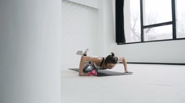Bir beyaz kıyafetler içinde spor salonunda egzersiz yapıyor giyimli Fitness sarışın kadın. Büyük pencereler kapalı Beyaz Dolgulu egzersiz yaparak Atletizm kız yaklaşıyor
