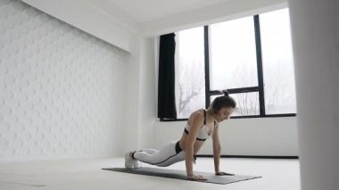 Sabah spor, egzersiz eğitim sırasında büyük windows yakınındaki spor salonunda genç fitness sarışın kadın çalışmaları. Beyaz spor giyindi