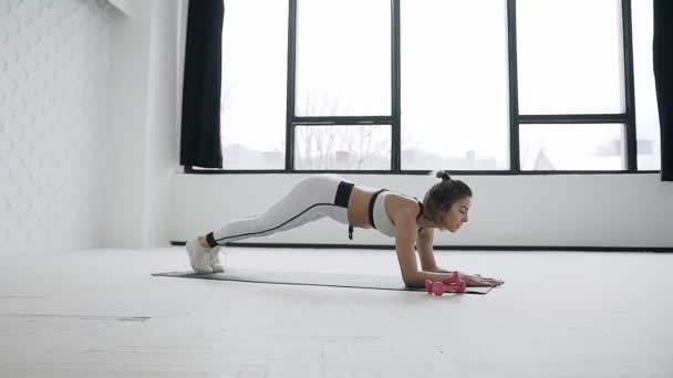Fitness kaukaski kobieta młody robi pilates rozgrzewka szkolenia ćwiczenia na nogi, ramiona aktywny tryb życia. Dziewczyna, rozciąganie ciała. Młoda kobieta wykonywania Piłat przenieść na maty — Wideo stockowe