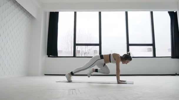 Athlétique blonde jeune femme ne planche de course dans le cadre de sa remise en forme croix. Salle de gym. Programme d'entraînement — Video