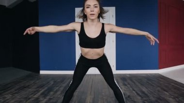 Egzersiz. Yeni başlayanlar için fitness ve spor öğreticiler. Kas ince genç kadın giyinmiş koyu spor giyim üst arka germe yapıyor, o öne eğilerek
