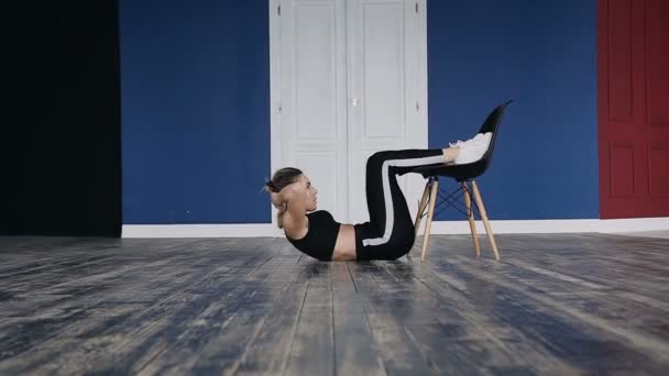 Una joven activa en un traje deportivo fortalece los músculos de la prensa con una carga de ejercicios, su peso es más pesado para una mayor carga en los músculos, la chica de fitness está en el club de fitness — Vídeo de stock