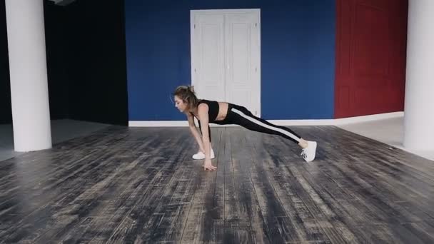 Mujer joven estirando sus piernas en yoga de pie ejercicio de estiramiento como parte de una rutina de fitness o estilo de vida activo. Chica fitness haciendo calentamiento antes del entrenamiento haciendo dedo del pie pierna tacto se estira en el interior en — Vídeos de Stock