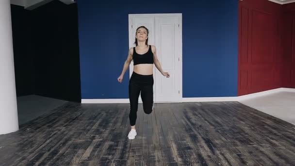 Jeune femme faisant des exercices de conditionnement physique à l'intérieur. Fit girl faire sauter et courir sur place dans le parc. Entraînement et remise en forme au gymnase. Femme athlétique attrayante faisant des exercices d'étirement — Video