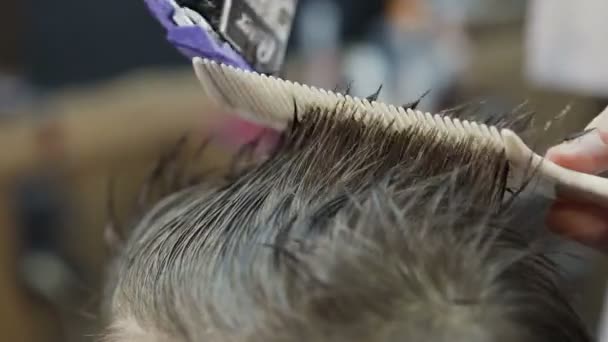 Κοντινό πλάνο του τρίμερ χτένισμα μαλλιών. Ανδρικό κούρεμα με ξυράφι ηλεκτρικό και χτένα. Επαγγελματία κομμωτή κοπής μαλλιά με κουρευτική μηχανή. Κουρείο — Αρχείο Βίντεο