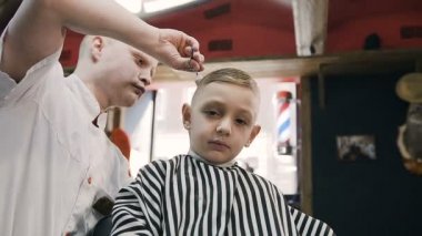 Hoş çocuk bir berber göz fotoğraf makinesine bir sandalyeye oturur ve her şey yolunda ve onun Kuaför ve yeni saç modeli hoşlanıyor eliyle gösterir. Çocuğu erkek Kuaför Salonu