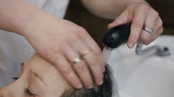 Γκρο πλαν. Στυλίστας πλένει τα μαλλιά του ο νεαρός άντρας στο κομμωτήριο ή κουρείο. Κομμωτήριο άνθρωπος πλύσιμο των μαλλιών του πελάτη του λίγο για την κατασκευή σύγχρονων κούρεμα σε κουρείο — Αρχείο Βίντεο