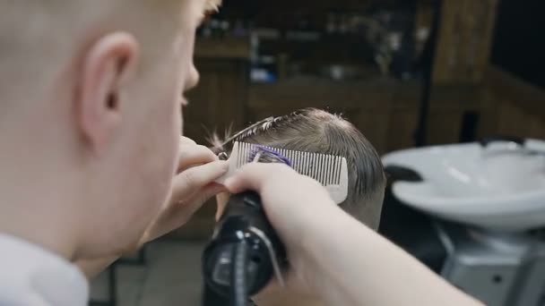 Cabeleireiro mestre barbeiro faz penteado e estilo para pequeno cliente com aparador e pente. Barbearia. Novo corte de cabelo e penteado para o belo menino — Vídeo de Stock