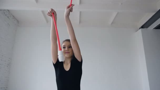 Sport och framgång. Tjej gymnast i svart sportssbody med rosa mace utbildning i sport skolan. Gymnastik i skolan. Träning av flicka på vit bakgrund — Stockvideo