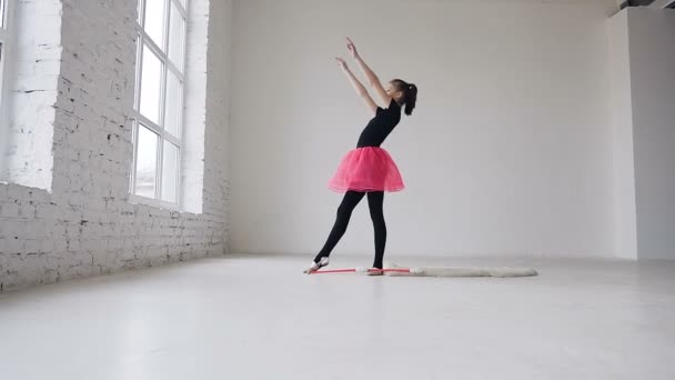 Linda gimnasta haciendo círculo con maza en las piernas en el estudio sobre fondo blanco. Escuela de gimnasia. Chica gimnástica — Vídeo de stock