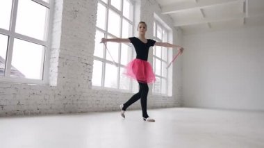 Exercive topuz Studio büyük pencereler yakınındaki beyaz arka plan üzerinde el ile iş ve kameraya gülümseyen sevimli sarı saçlı kız. Alttan görüntülemek