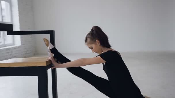 Söt smal tjej gör stretching benen sitter i studio inomhus. Attraktiva gymnast utbildning flexibilitet, flicka ökar elasticitet i muskler och förbättrar rörlighet i lederna. Ordentlig stretching — Stockvideo