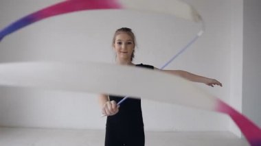 Renkli şerit beyaz Studio kamera önünde iplik şirin zarif jimnastik portresi. Jimnastik, renkli bant ile ritmik kız bak kamerada