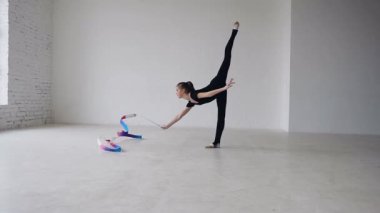 Küçük jimnastik jimnastik yaparken siyah gövde renkli bir şerit beyaz Studio ile egzersiz. Sevimli kız germe egzersiz spor salonunda yapar.
