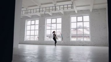 Ritmik Jimnastik: siyah gövde kız büyük pencereler yakınındaki spor okulda jimnastik egzersiz renkli bir şerit ile gerçekleştirmek. Bale Okulu