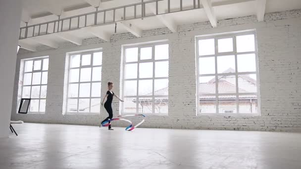 Ginástica rítmica: Menina de corpo negro realizar exercício de ginástica com uma fita colorida na escola de esporte no fundo janelas na escola de ginástica. Escola de Ballet. Exercício — Vídeo de Stock