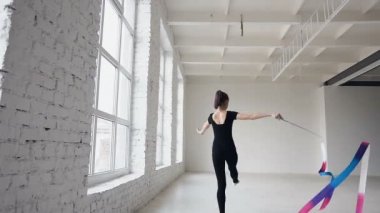 Sarışın sevimli kız dans ritmik jimnastik, pencerenin önünde siyah elbise renkli kurdele ile modern. Çekici kadın jimnastikçi ile kurdele jimnastik okul veya bale atlama