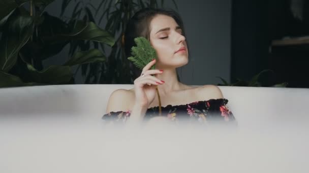 Beautiful young woman relaxing in hot bath spa resort. Attractive Asian tourist by in hot bath and green flowers on background . Cute girl with eyes closed pampering herself during vacation holiday — Stock Video