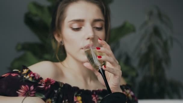 Porträtt av en söt ung kvinna som dricker champagne i badrummet. Ung vacker kvinna dricker champagne avkopplande i ett varmt bad. Ung flicka dricker champagne — Stockvideo
